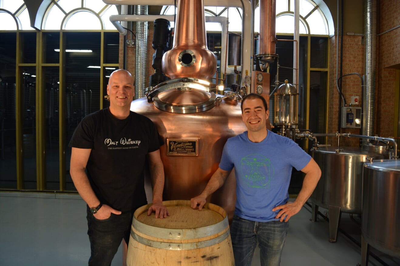 Distillers Jacques Tremblay and Daniel Pleznik pose in front of a fermenter at Bridgeland Distillery. 