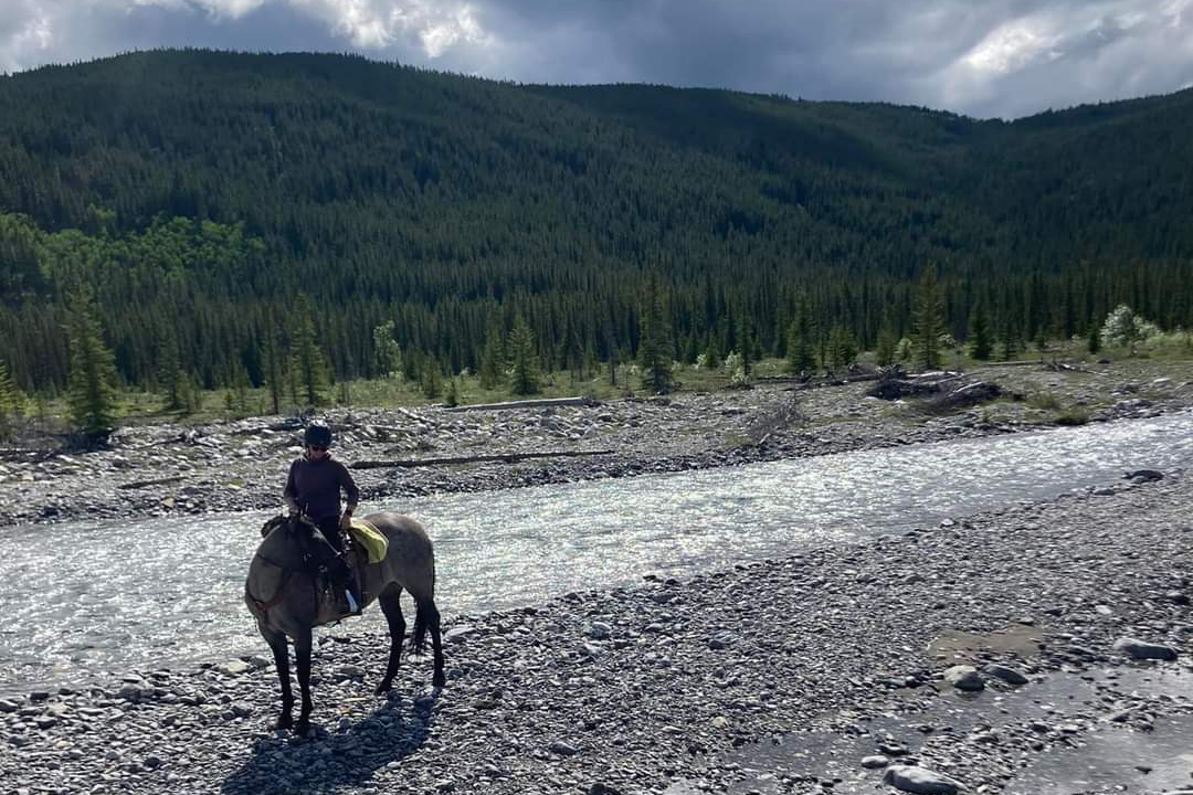 The trails are what drew us to camping with horses. Here I'm sitting on my mare by the river with foothills in the background. 