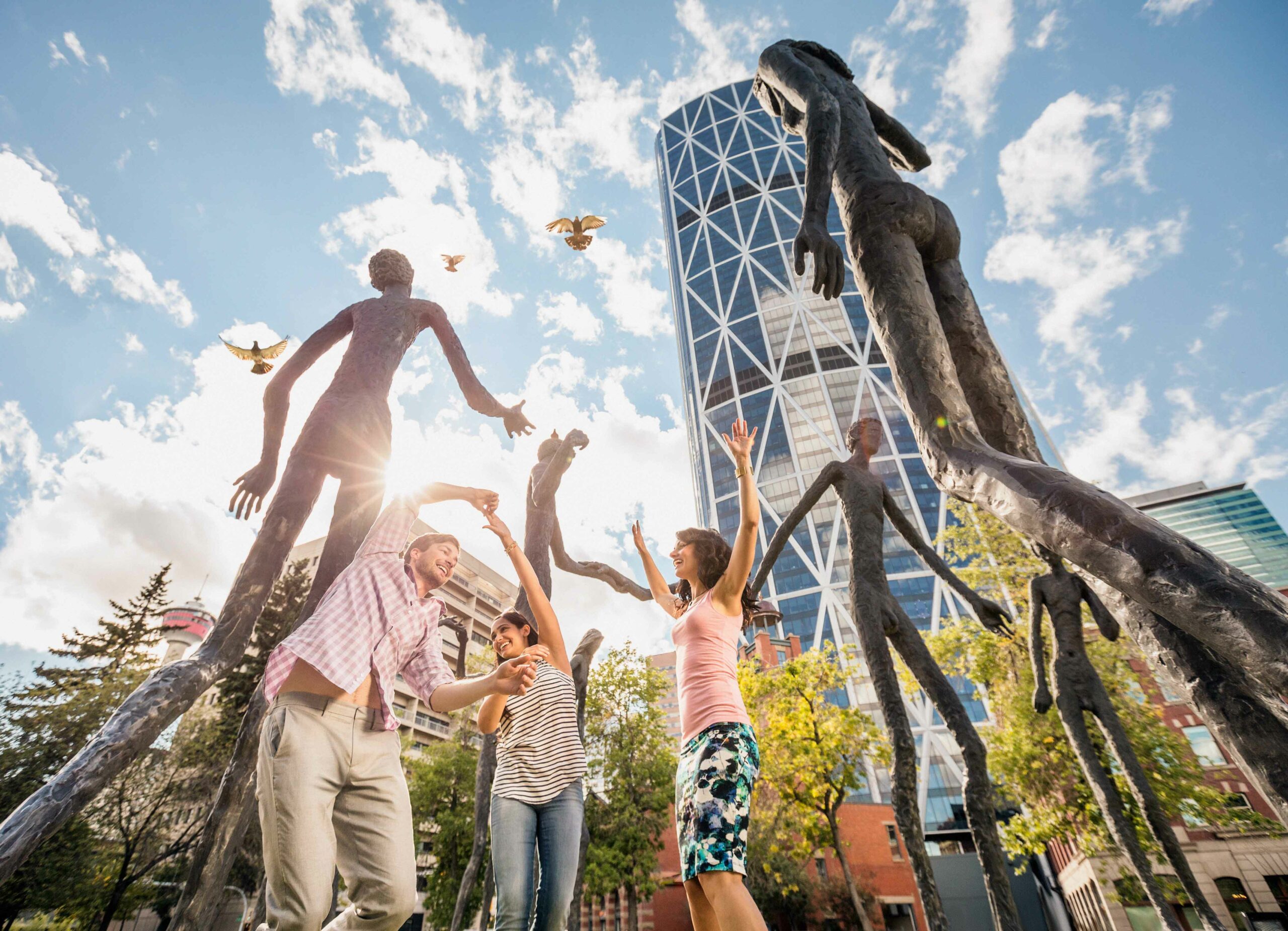 A family dances under the Family of Man public art installation in Calgary. This dynamic photo shows off the potential of this photo op in the city.