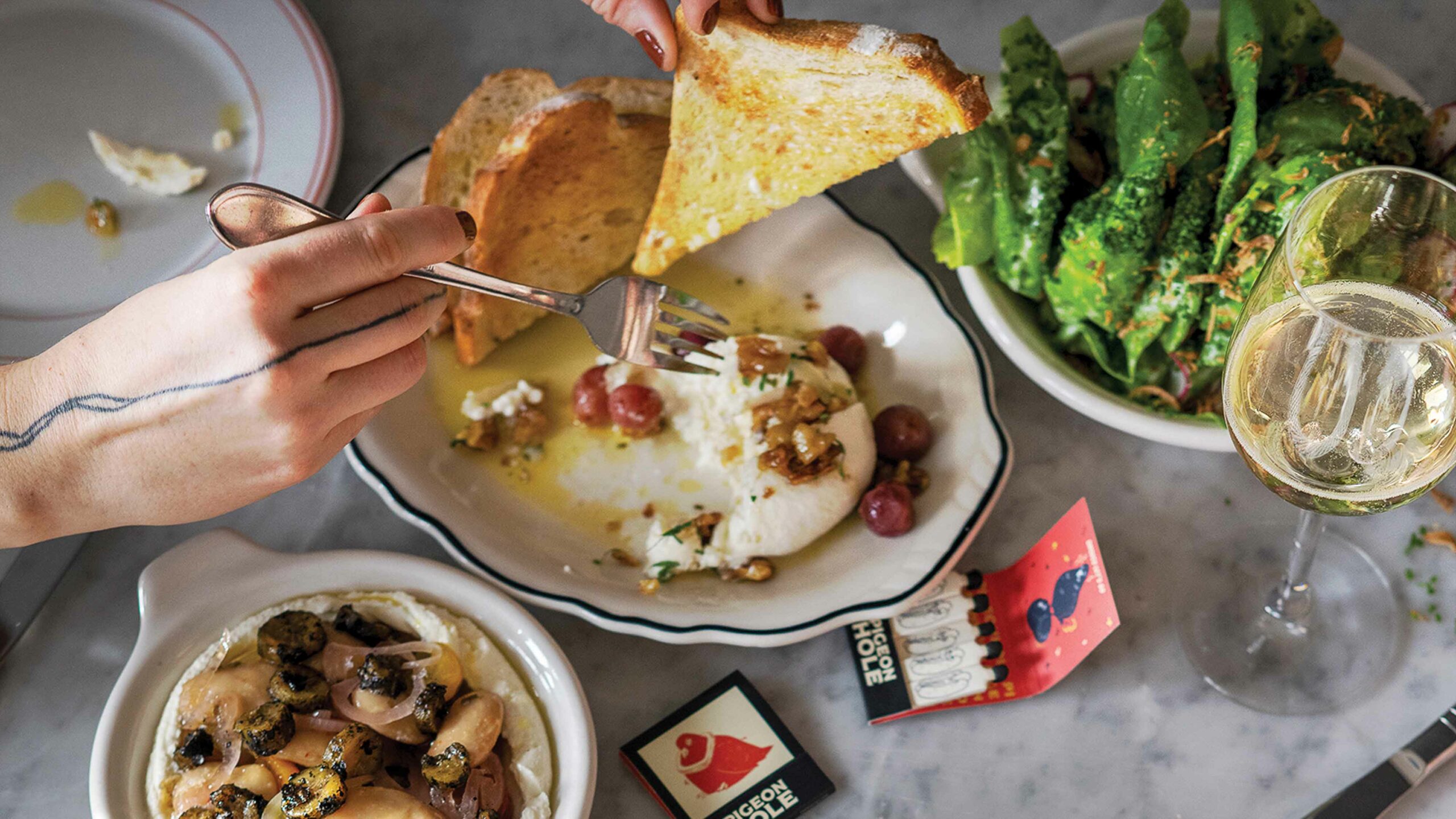 A person eats from a variety of dishes at Pigeonhole during a happy hour