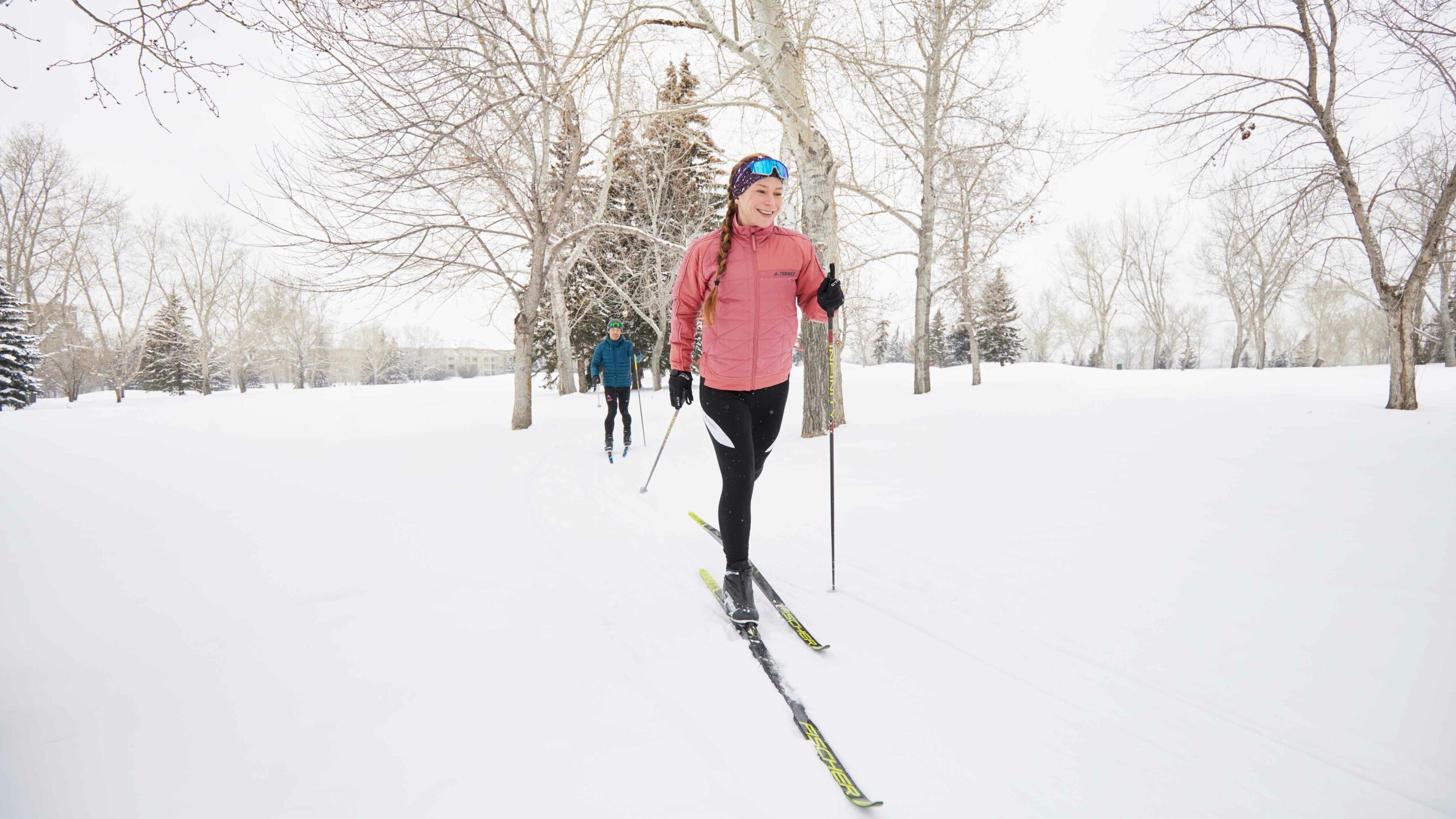 Two people cross-country ski on a golf course in Calgary as an example of outdoor things to do in Calgary. 
