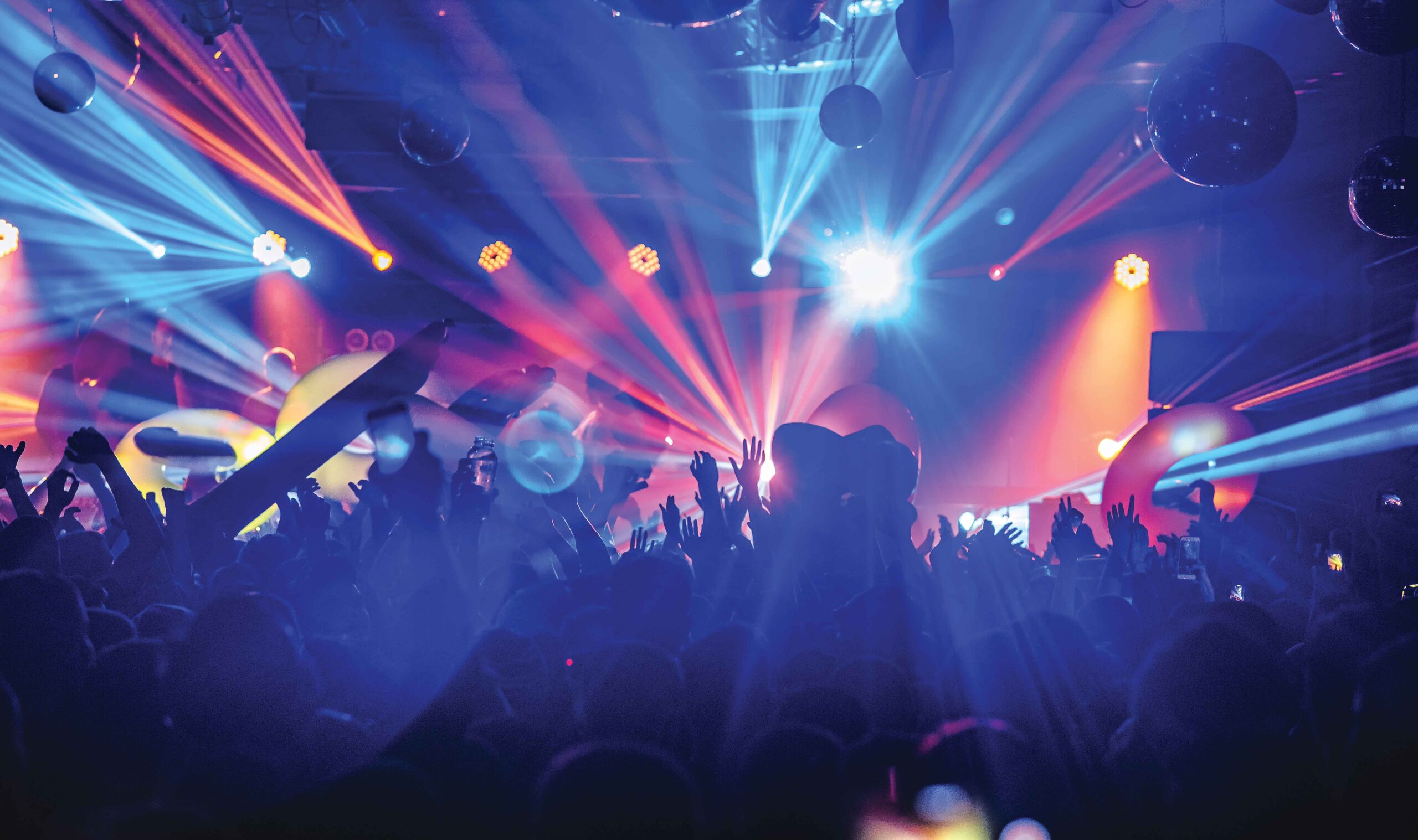 Colourful lasers light up a rave scene with dancers partying. 