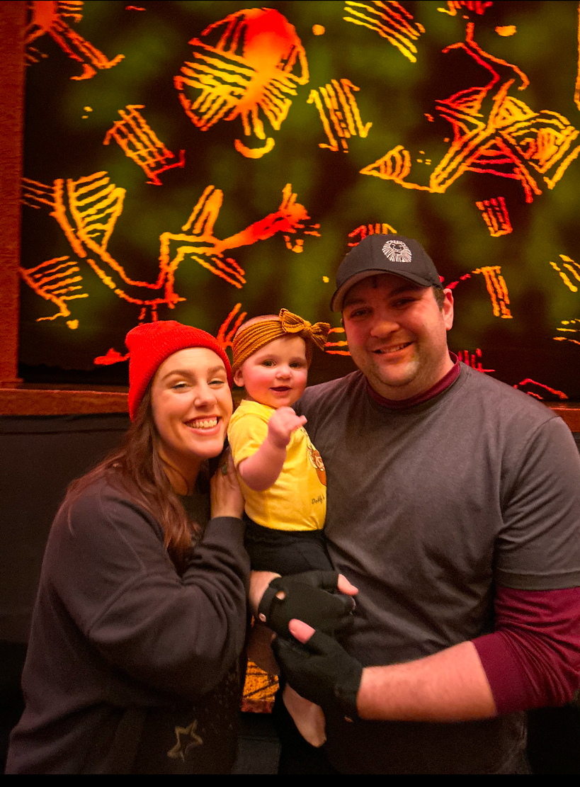 Danny Grumich who plays Pumbaa in Disney's The Lion King poses with his wife, Meryn, and new daughter, Gracie.